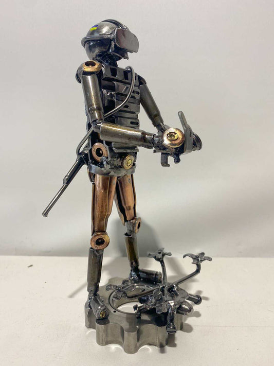 Sculpture of Ukrainian soldier operating FPV drone made from frontline shells