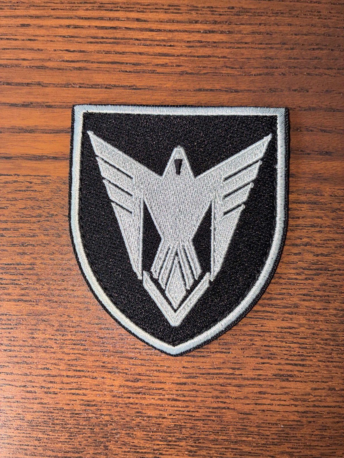 9th Unmanned Systems Brigade patch in black and grey with a stylized eagle design embroidered on fabric