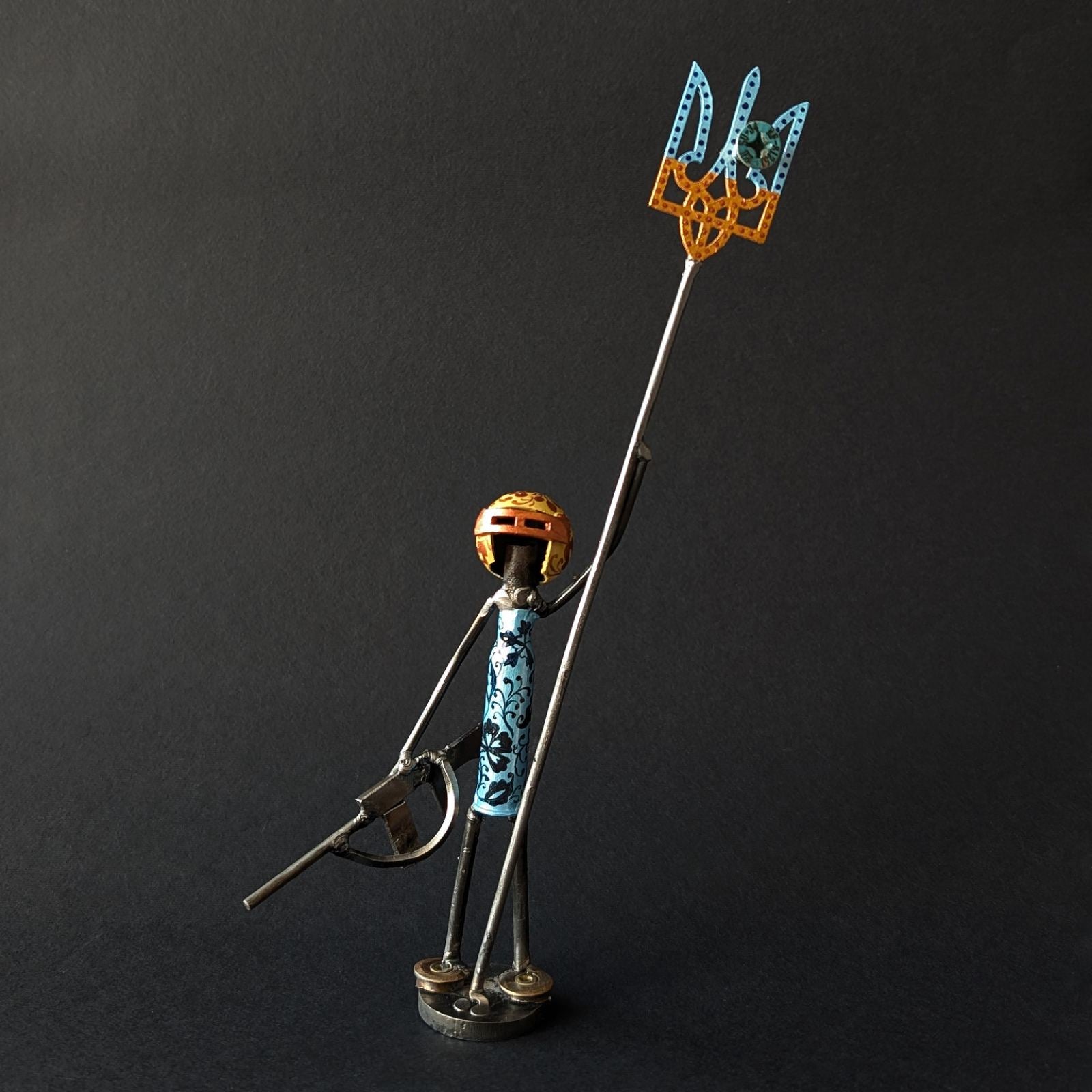 Metallic figurine of a character holding a tryzub against a black background