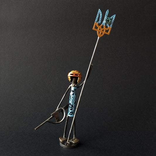 Metallic figurine of a character holding a tryzub against a black background