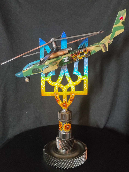 Destroyed KA-52 attack helicopter model impaled on Tryzub sculpture by Hisoshi Art Studio