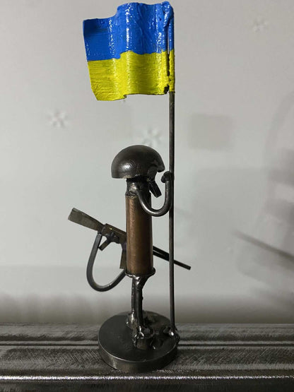 Mini-Soldier sculpture holding Ukrainian flag, 17cm tall by Hisoshi Art Studio made from frontline shells