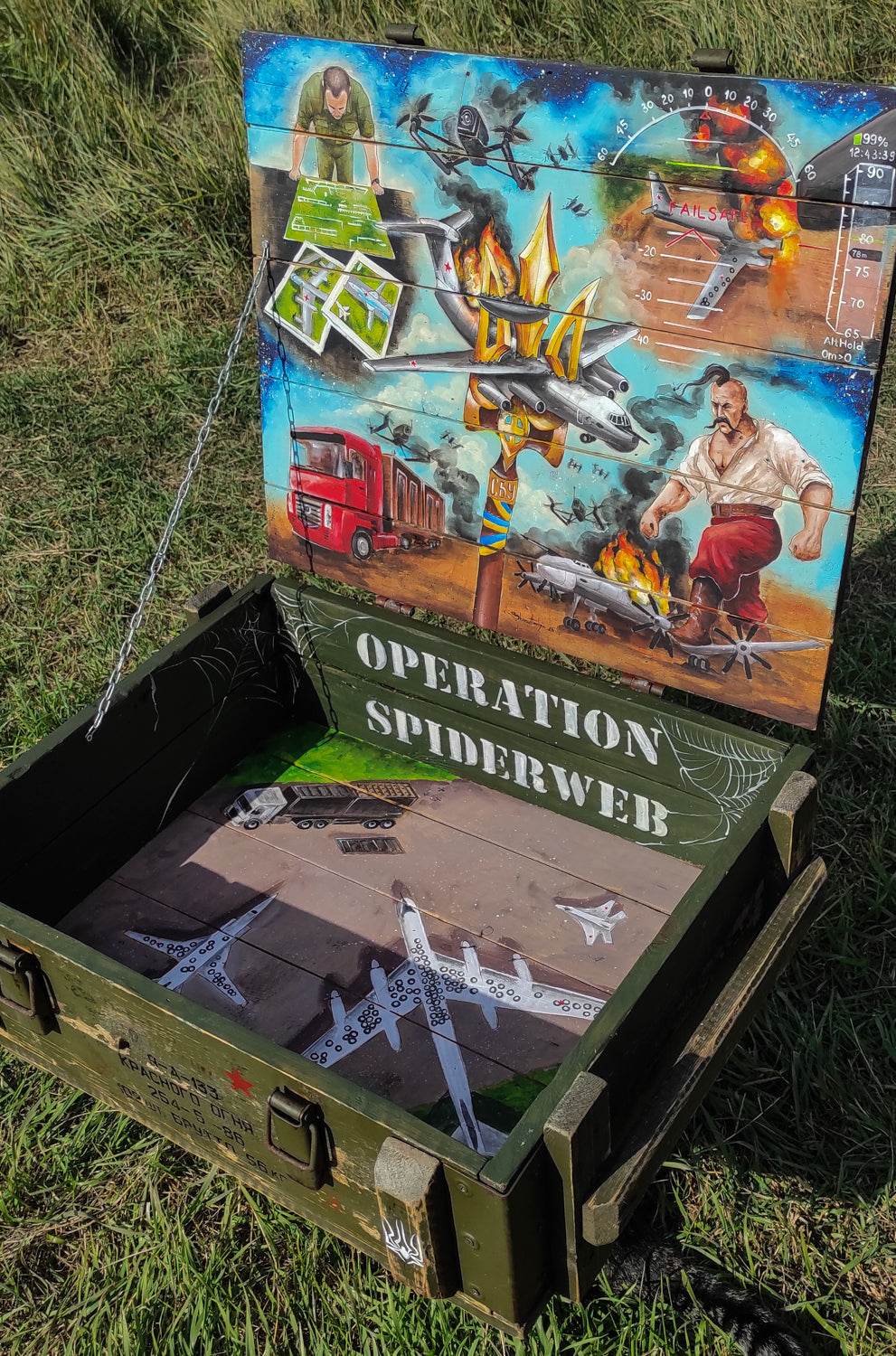 Operation Spiderweb painted ammunition box by Tanya Shacun with cat nearby