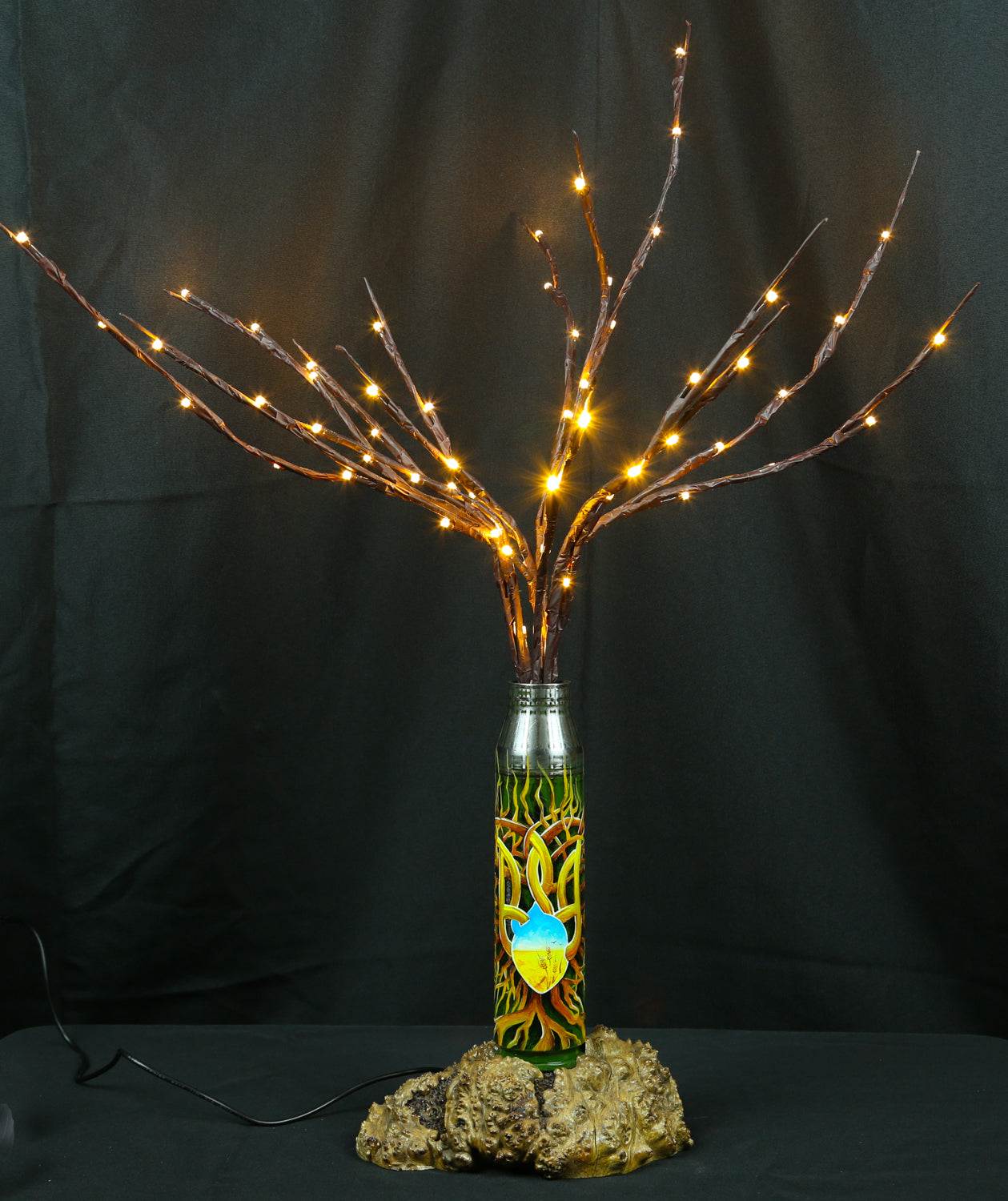 Tree of light sculpture growing from spent Gepard shell next to European 220V outlet designed by Tanya Shacun