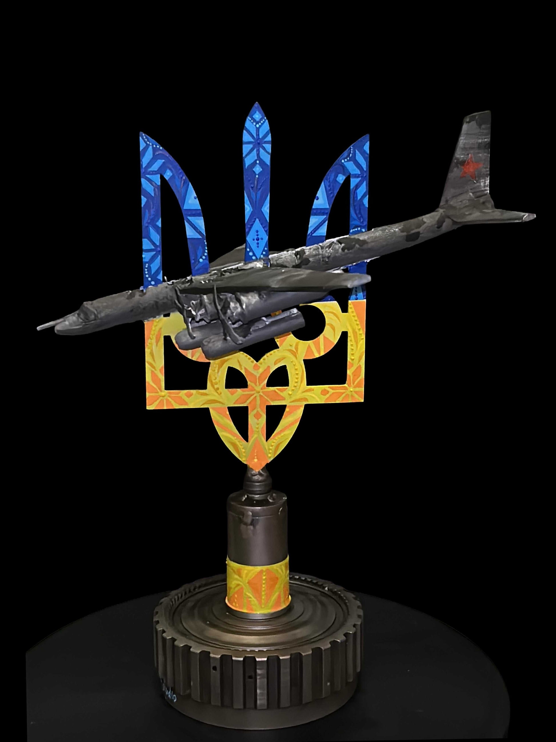 TU-95 model aircraft impaled on golden Tryzub sculpture by Hisoshi Art Studio