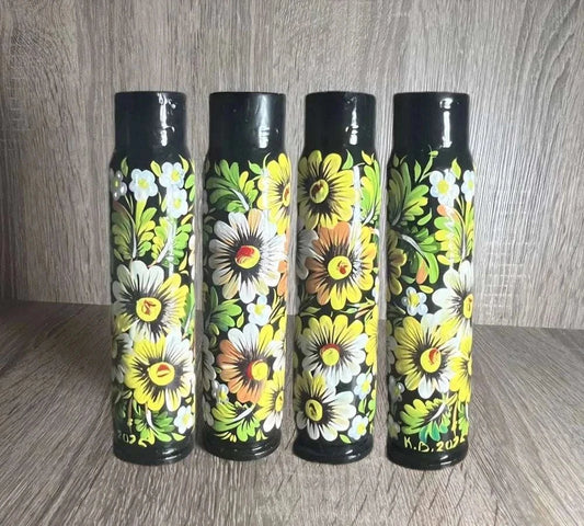 Ukrainian reward system: four black shell casings hand-painted with bright yellow and white flowers and green leaves