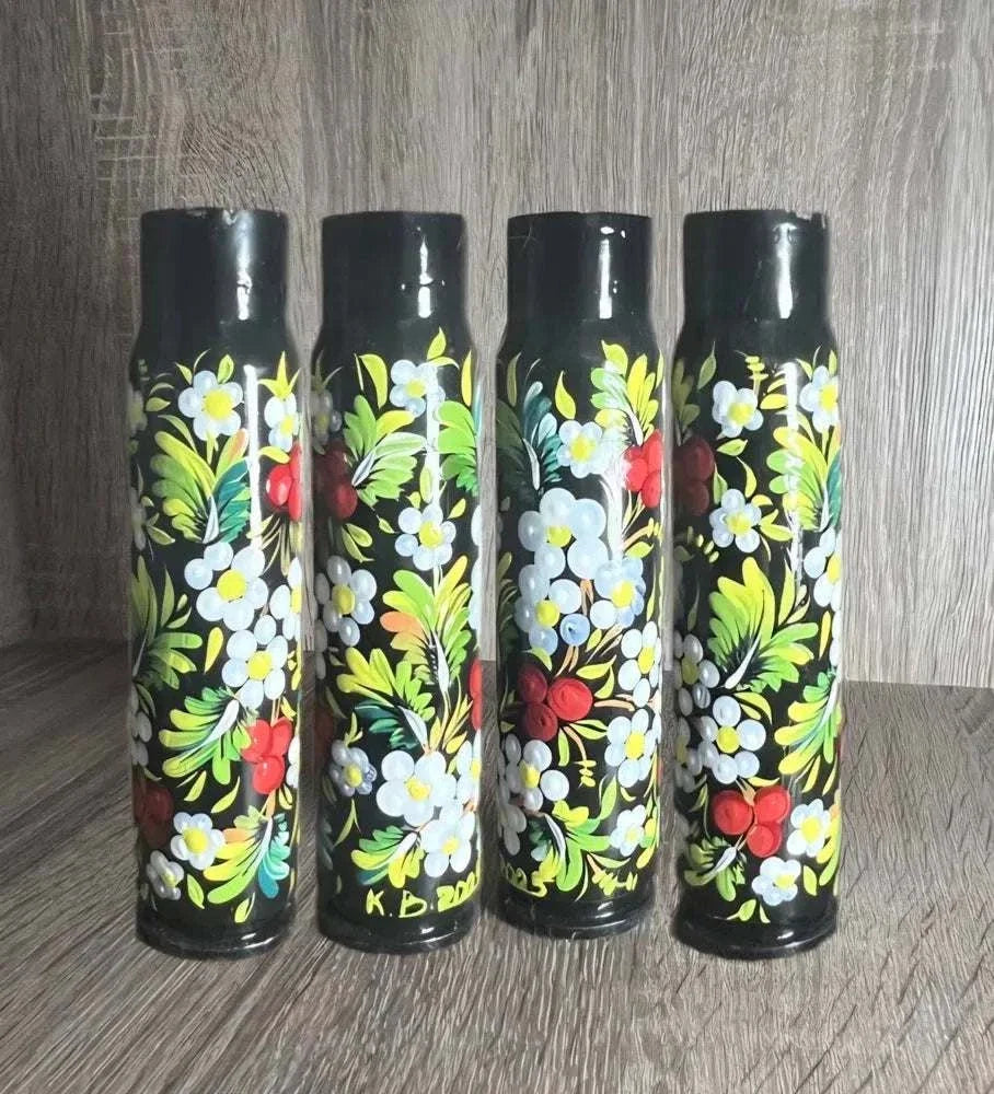 Ukrainian reward system: four black shell casings hand-painted with white flowers, red berries and green leaves