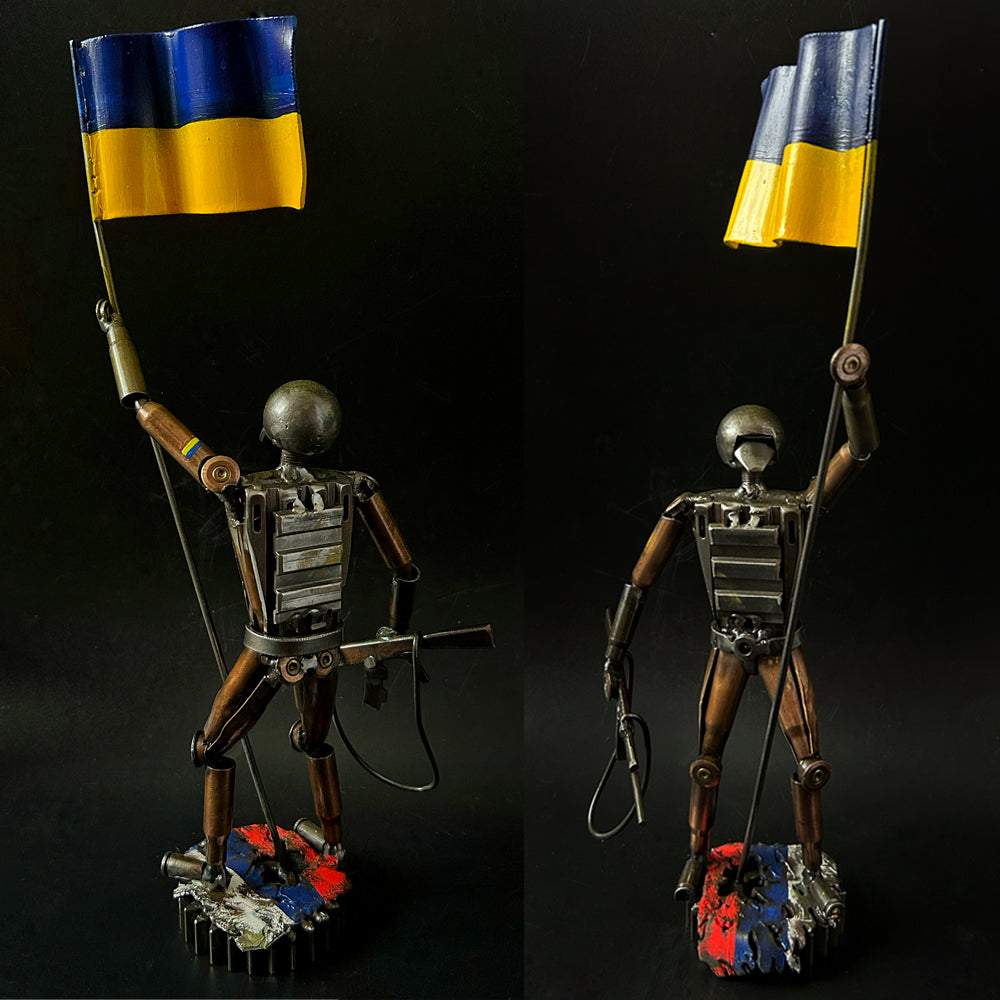 Ukrainian soldier sculpture with flag standing on Russian rag made from frontline shells