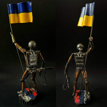 Ukrainian soldier sculpture with flag standing on Russian rag made from frontline shells