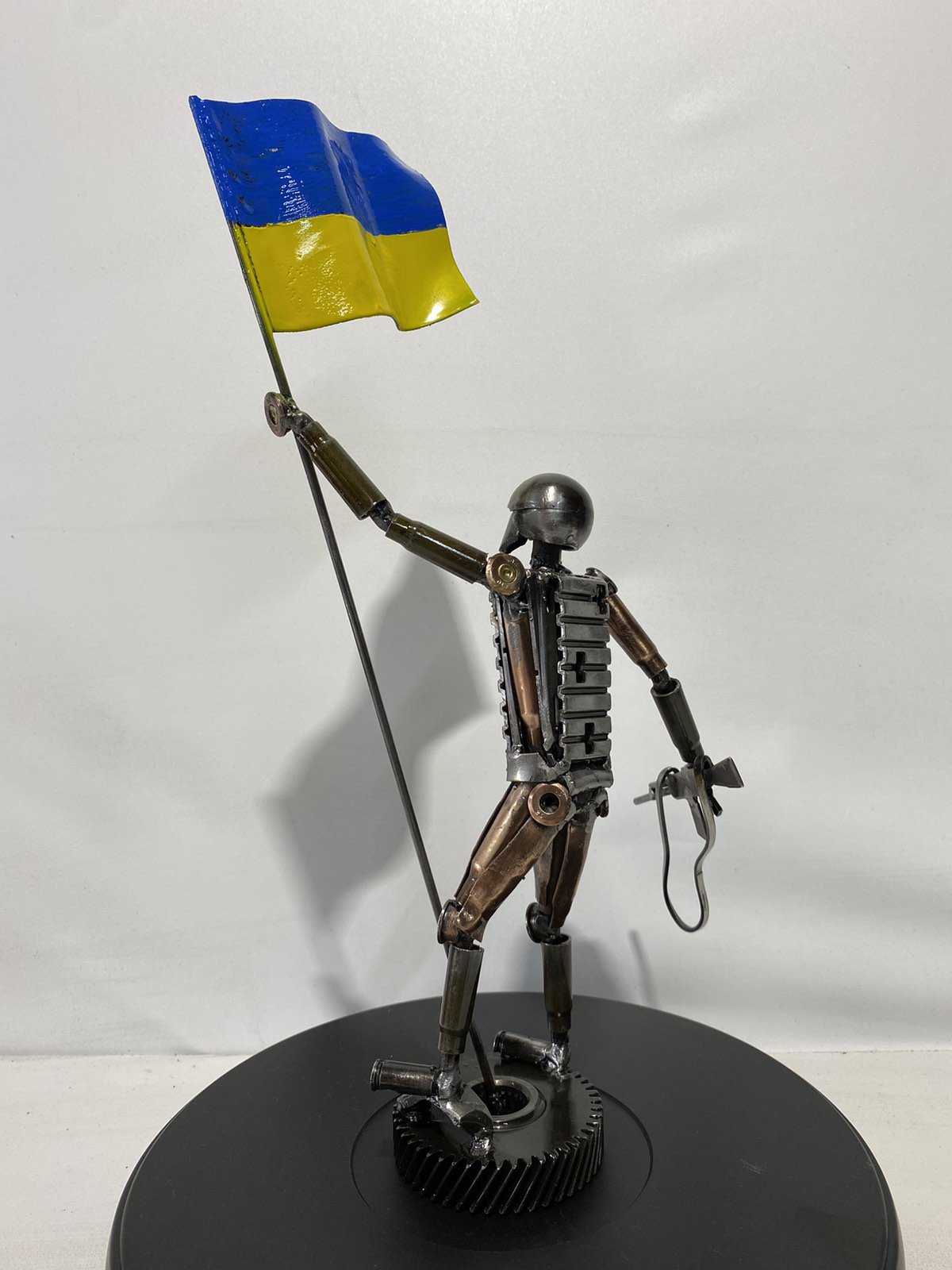 27cm sculpture of Ukrainian soldier holding flag made from frontline shells by Hisoshi Art Studio