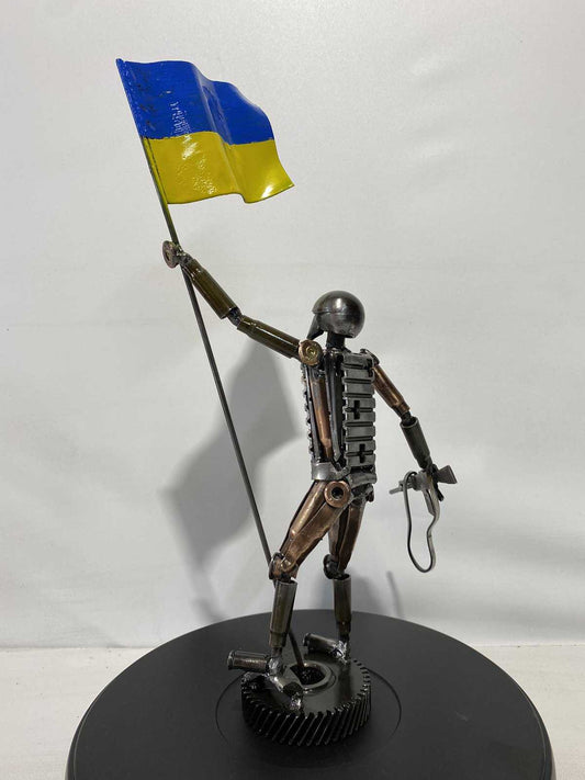 27cm sculpture of Ukrainian soldier holding flag made from frontline shells by Hisoshi Art Studio