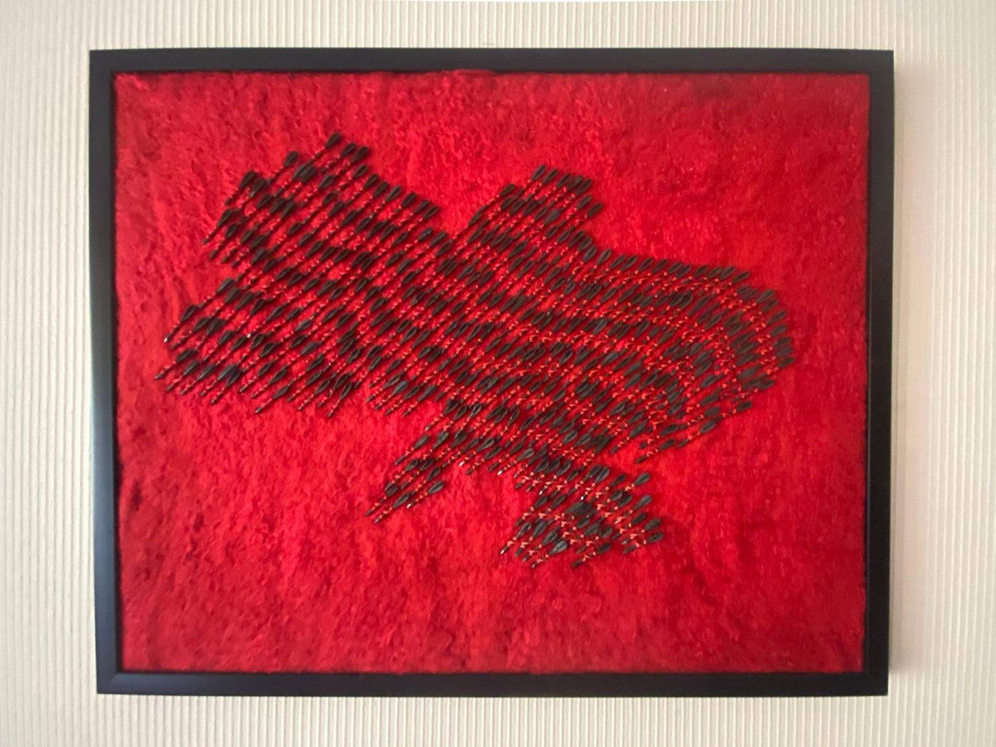 Wool map of Ukraine in red with 300 fletchettes symbolizing air raid sirens and missile attacks