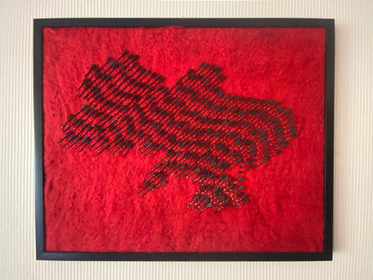 Wool map of Ukraine in red with 300 fletchettes symbolizing air raid sirens and missile attacks